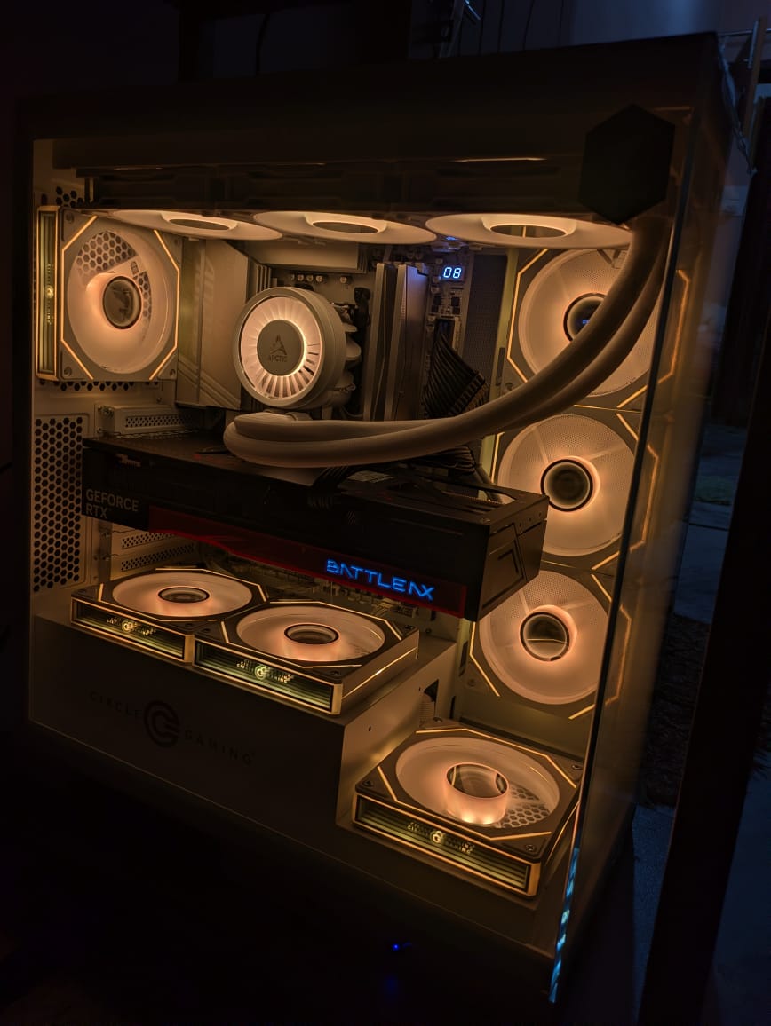 Inside a white PC case lit in warm orange: an RTX 5070 Ti in the middle, an Arctic liquid cooler, and rows of ring-lit fans on the top, side, and bottom.